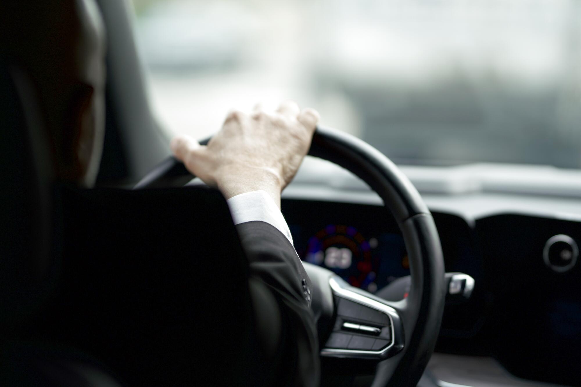 Professional chauffeur with a hand on the steering wheel